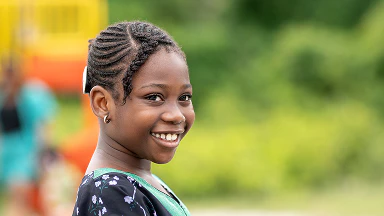 A young individual standing outdoors near a playground