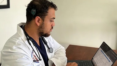 Um médico residente com um implante coclear olha seu notebook