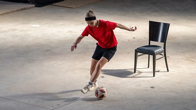 Uma adolescente com uma camiseta vermelha joga futebol