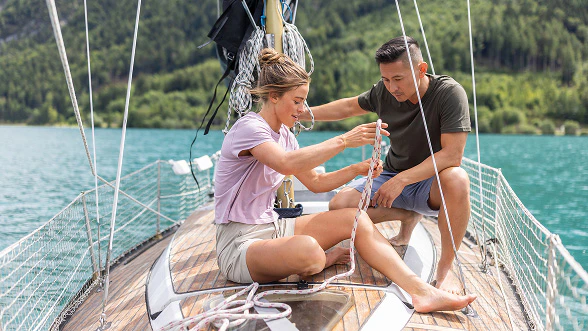 A woman and a man prepare knots on a sailing boat