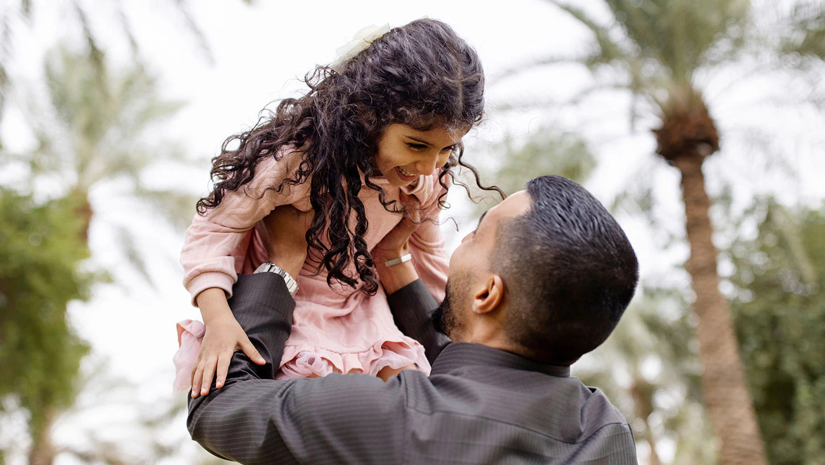 A father playfully throws his daughter in the air
