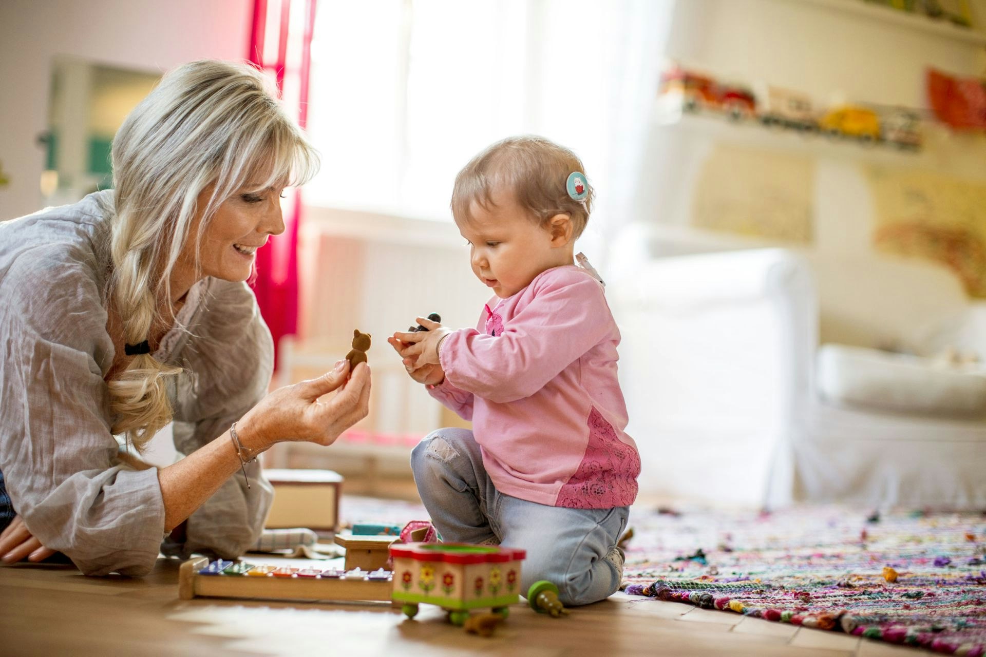 Less than 12-month old baby with a cochlear implant and mother playing on the ground with toys.